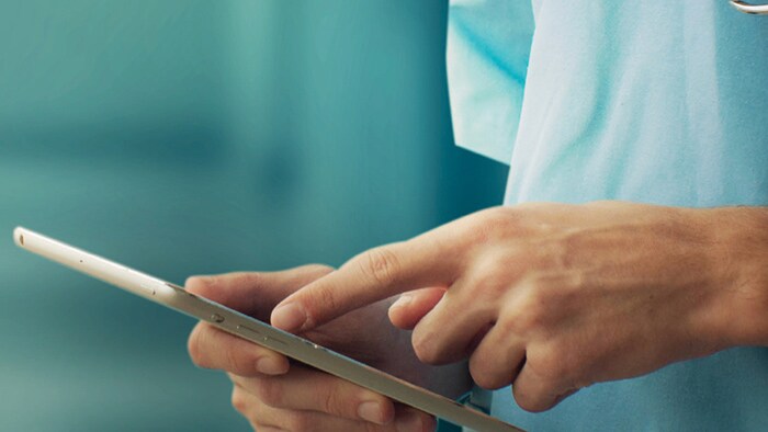 Doctor in scrubs using iPad in hand